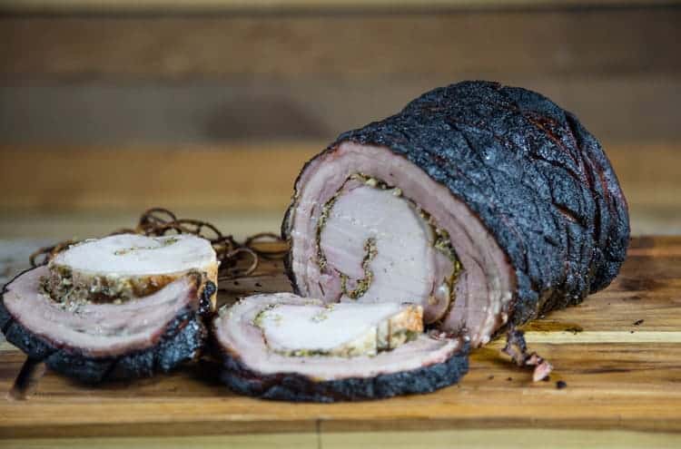 Grilled Porchetta, holiday roast, sliced on a cutting board, showing all the layers and filling