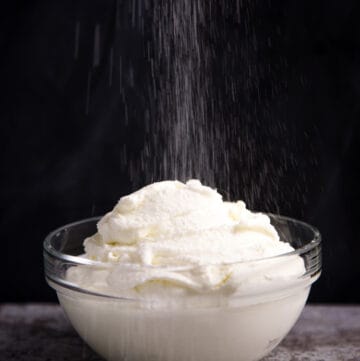a bowl of homemade whipped cream sprinkled with powdered sugar