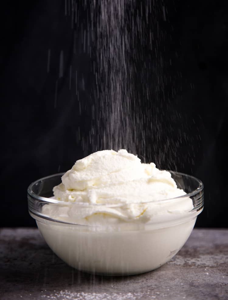 a bowl of homemade whipped cream sprinkled with powdered sugar