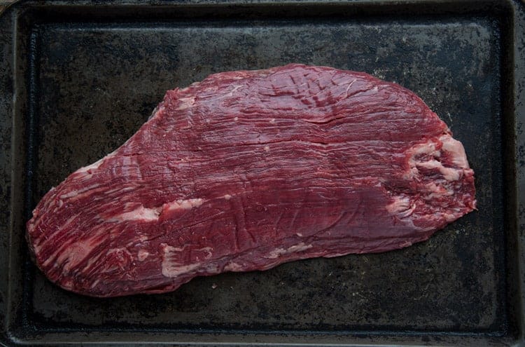 Raw flank steak on a sheet pan