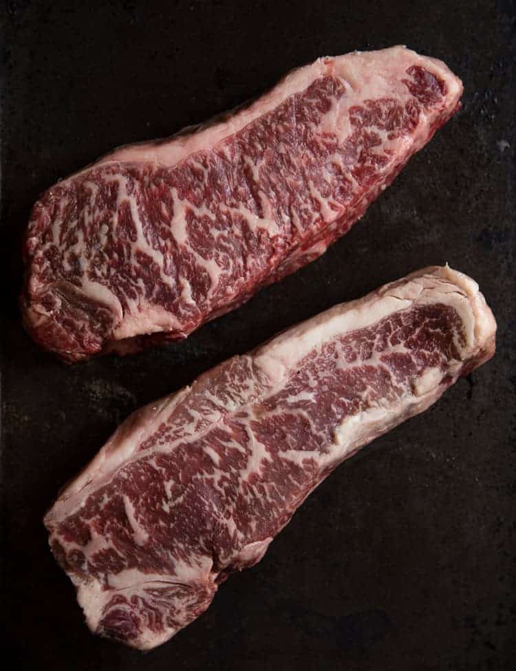 Two raw steaks with lots of marbling