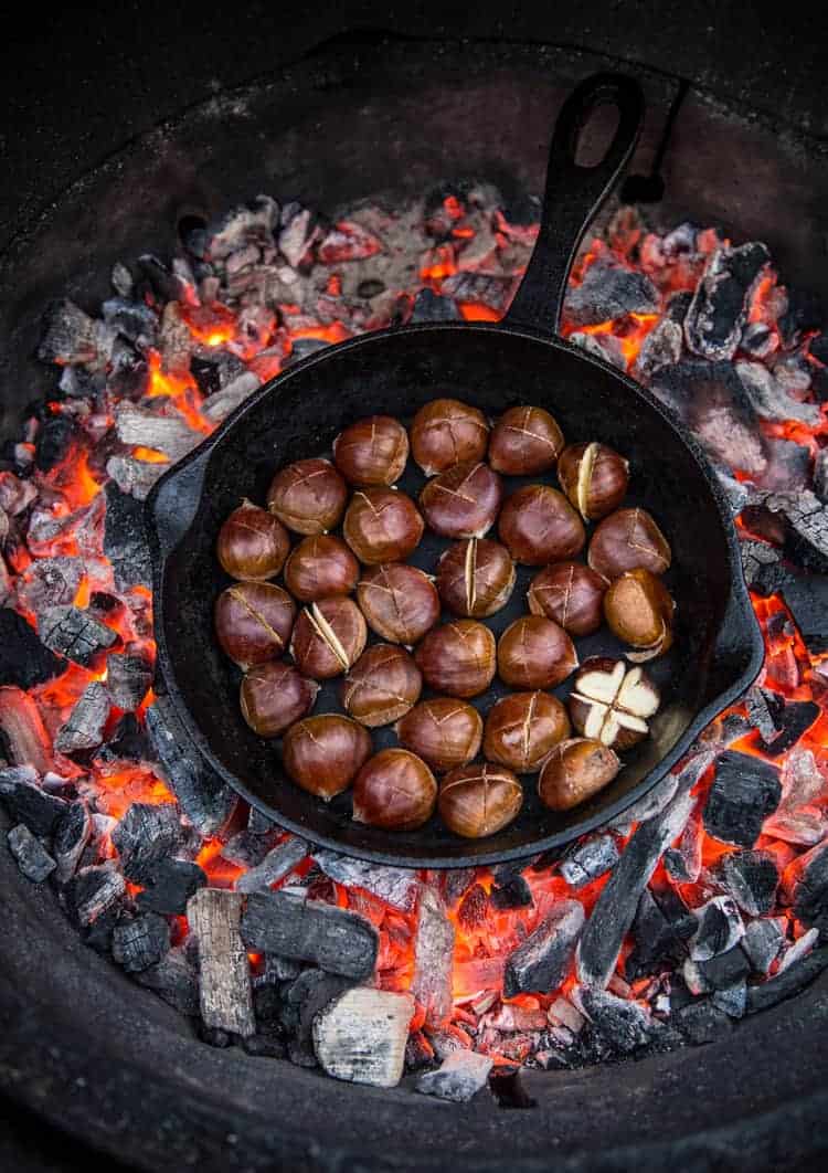 Roasted chestnuts in a cast iron skillet in a fire pit