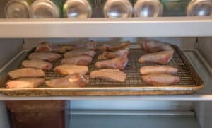 Chicken wings dehydrating in a refrigerator.