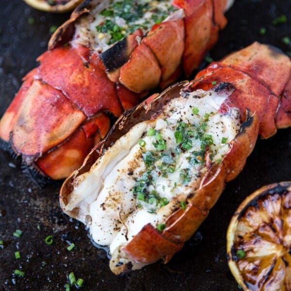 Grilled lobster tails with herb compound butter and grilled lemons.