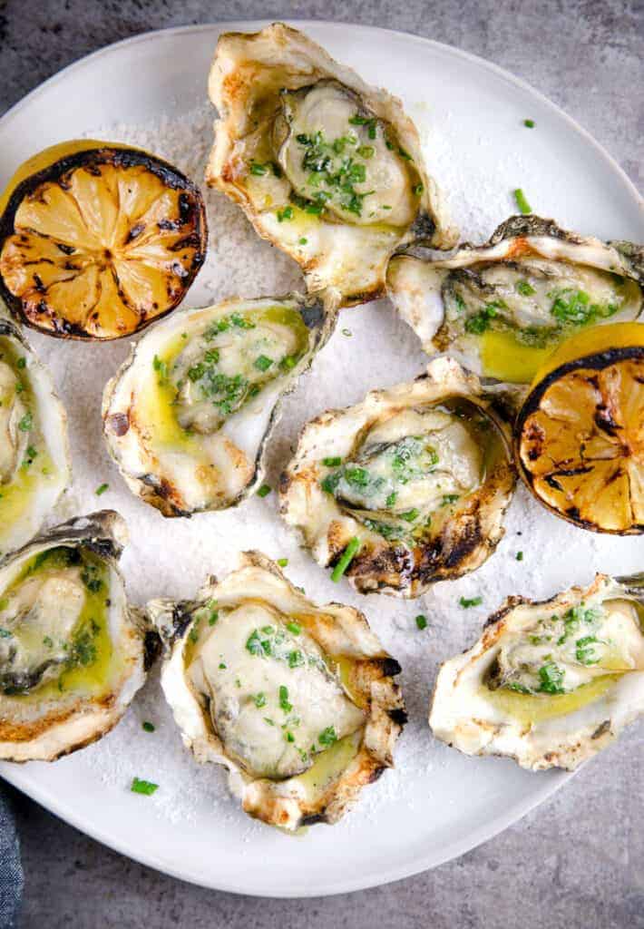 A plate of grilled oysters and grilled lemons