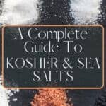 Small piles of kosher and sea salt on a black slate plate