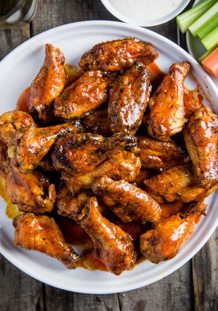 A Large plate of smoked chicken wings served with wine and celery