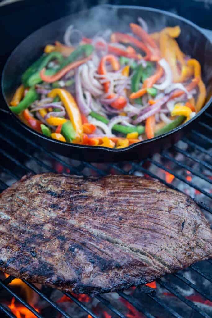 Flank Steak, onions and peppers on the grill for steak fajitas