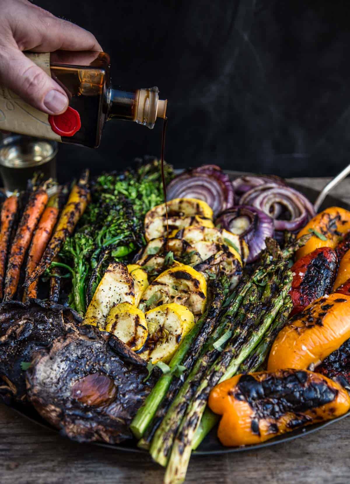 Drizzling aged balsamic vinegar over grilled vegetables.