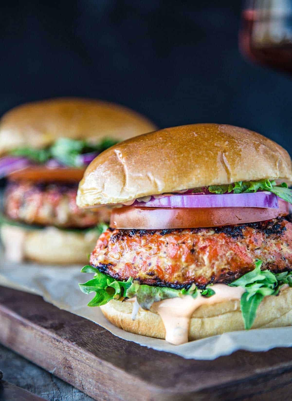 A Grilled Salmon Burger topped with classic toppings and a chipotle aioli.
