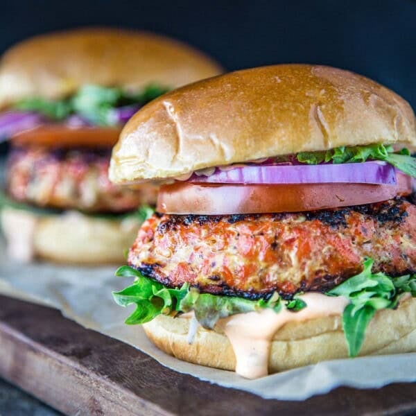 A Grilled Salmon Burger topped with a Chipotle Lime Mayo on a serving board.