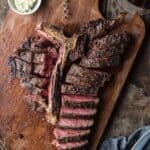 A Grilled T-Bone Steak sliced up and served with a glass of wine