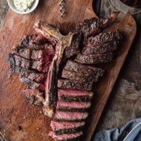 A Grilled T-Bone Steak sliced up and served with a glass of wine