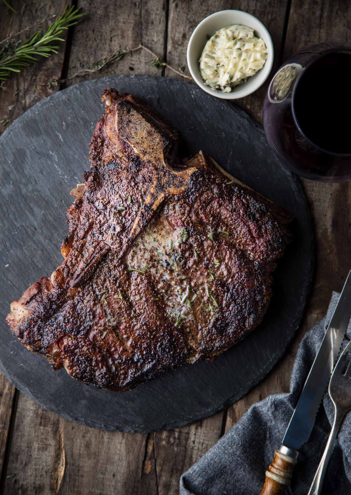 T-bone steak on a platter with a glass of cabernet sauvignon wine.