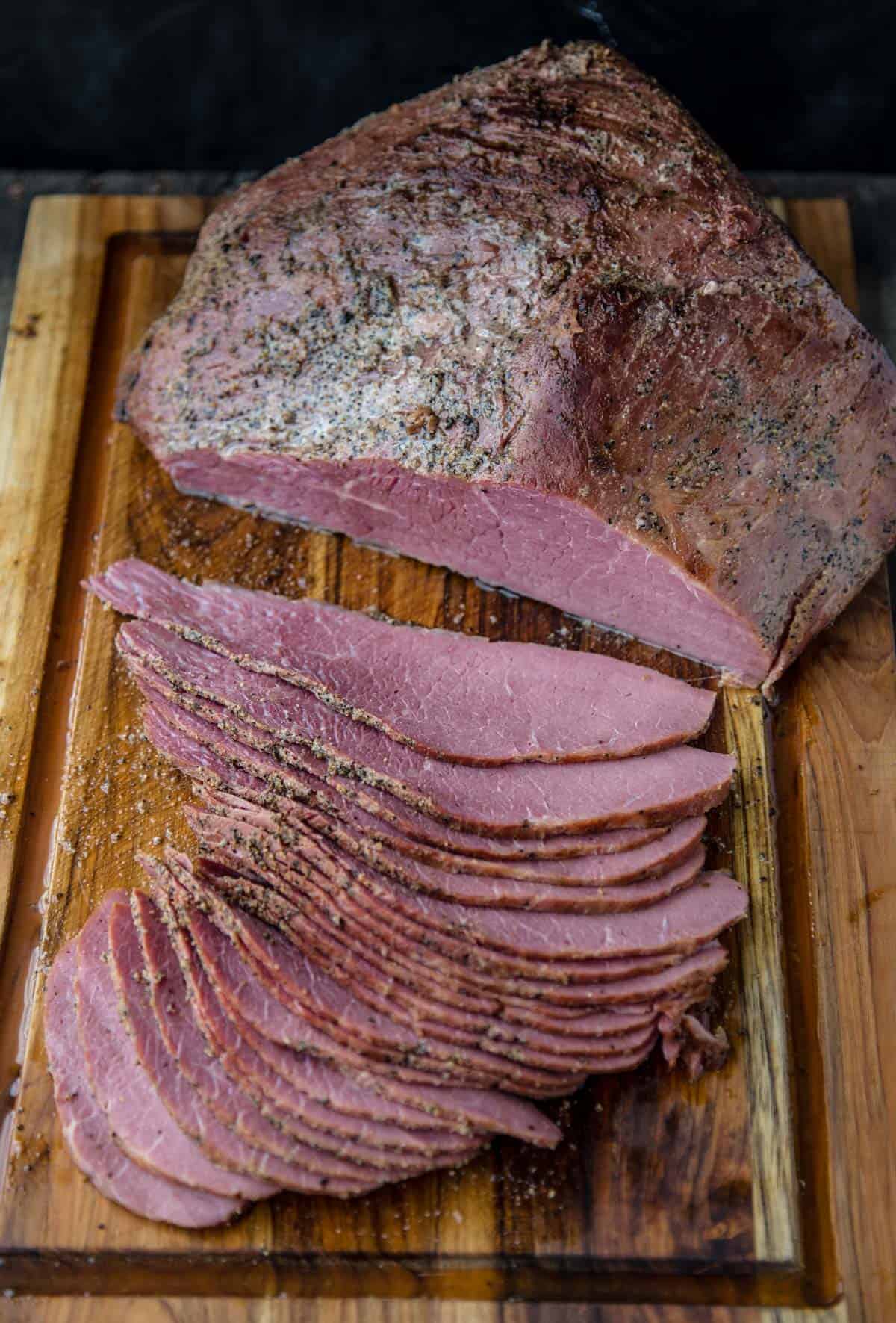 A smoked corned beef sliced into thin strips on a cutting board.