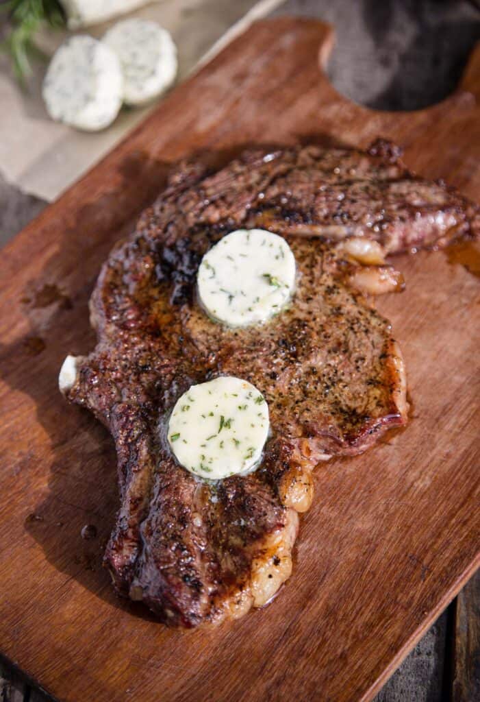 A grilled ribeye steak topped with an herbed compound butter