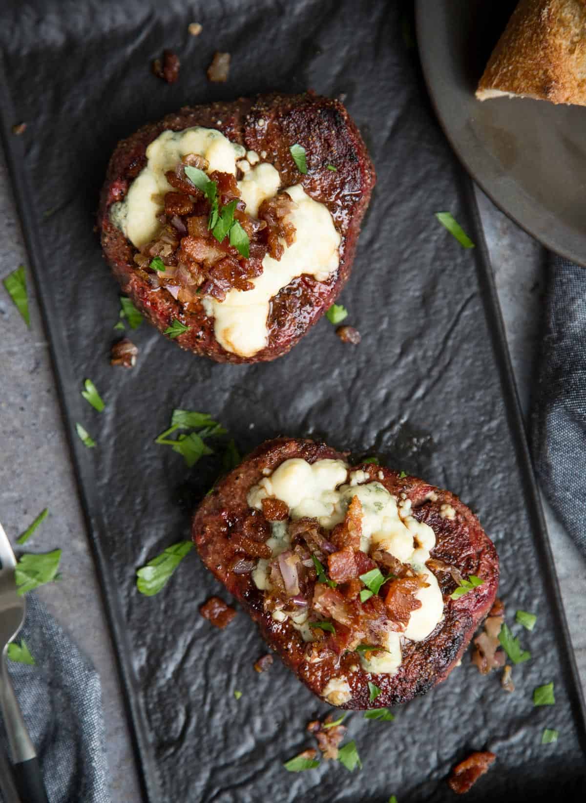 Two Grilled Filet Mignon Steaks topped wit Blue Cheese, Caramelized Onions, and Bacon