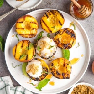 A platter of grilled peaches topped with ice cream and smoked honey