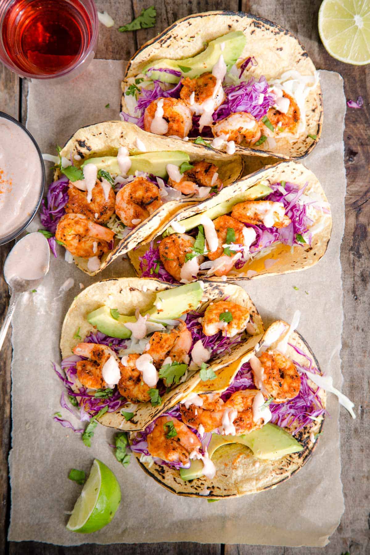 5 Grilled Shrimp Tacos on a wood platter with a glass of rosé wine