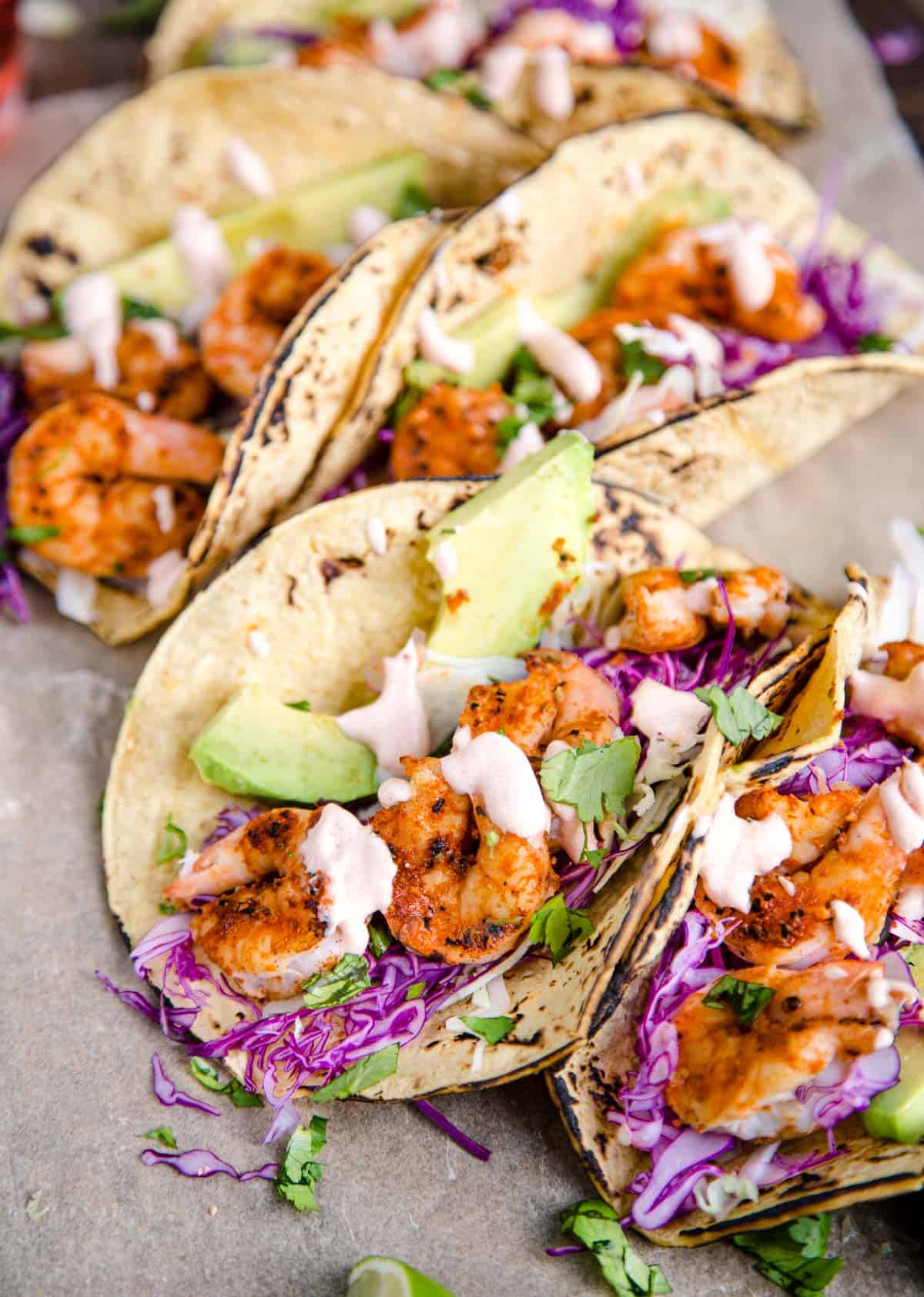 A platter of grilled shrimp tacos topped with a lime crema
