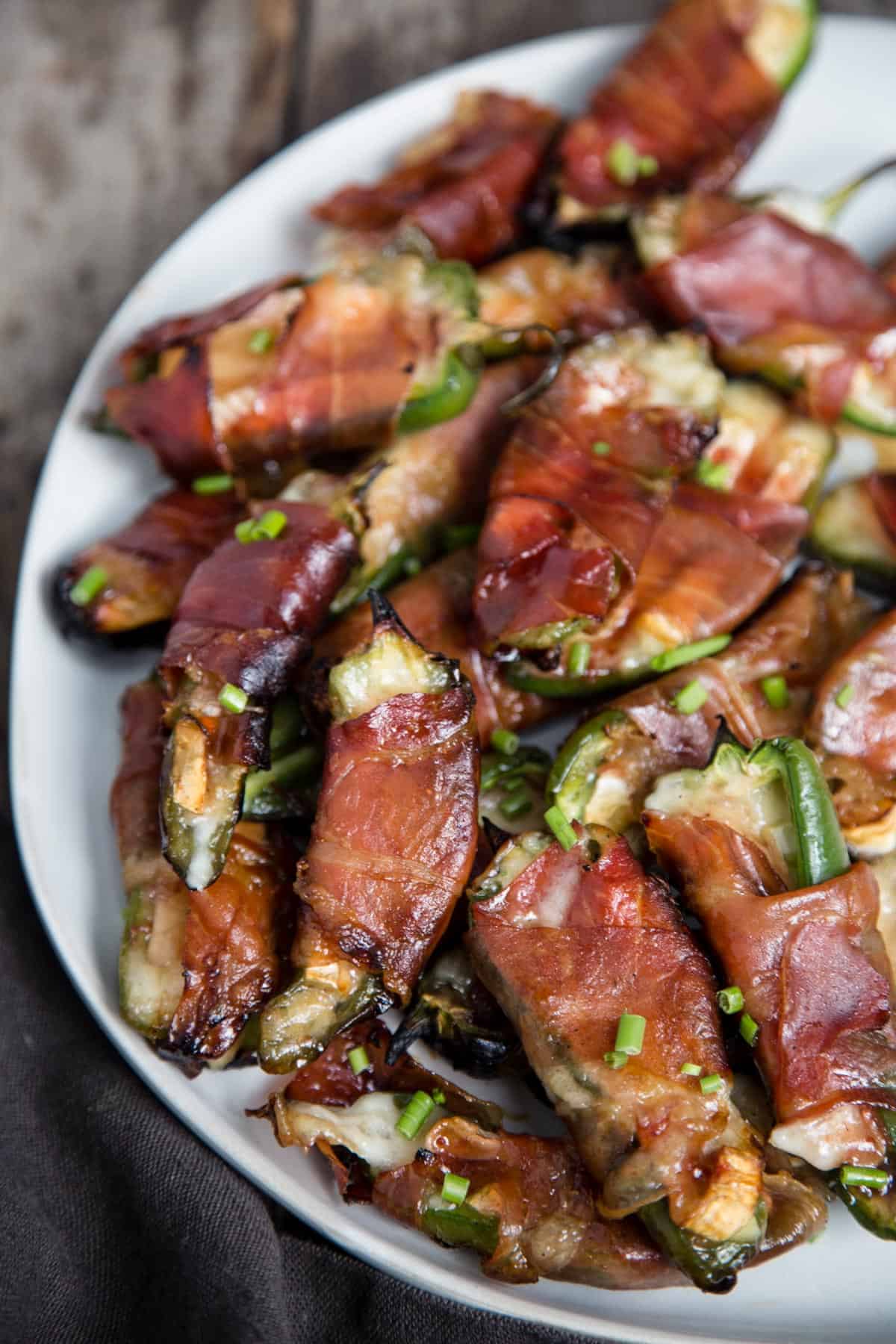 A platter of Jalapeno Poppers filled with brie cheese and wrapped with prosciutto. 