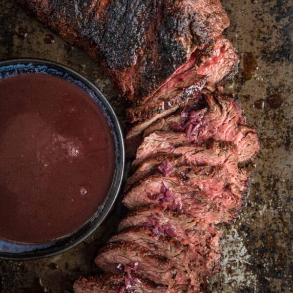 sliced tri tip with bowl of red wine sauce