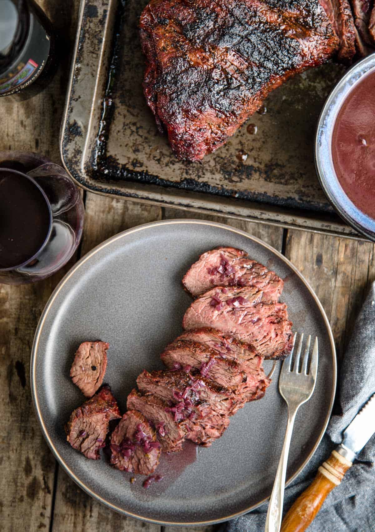 Slices of grilled Tri Tip on a plate served with a glass of Zinfandel red wine