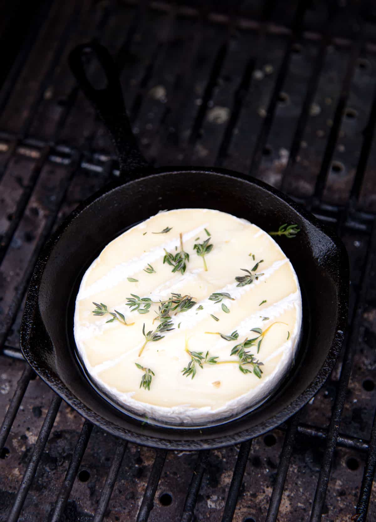 Brie cheese in a cast iron pan on the grill