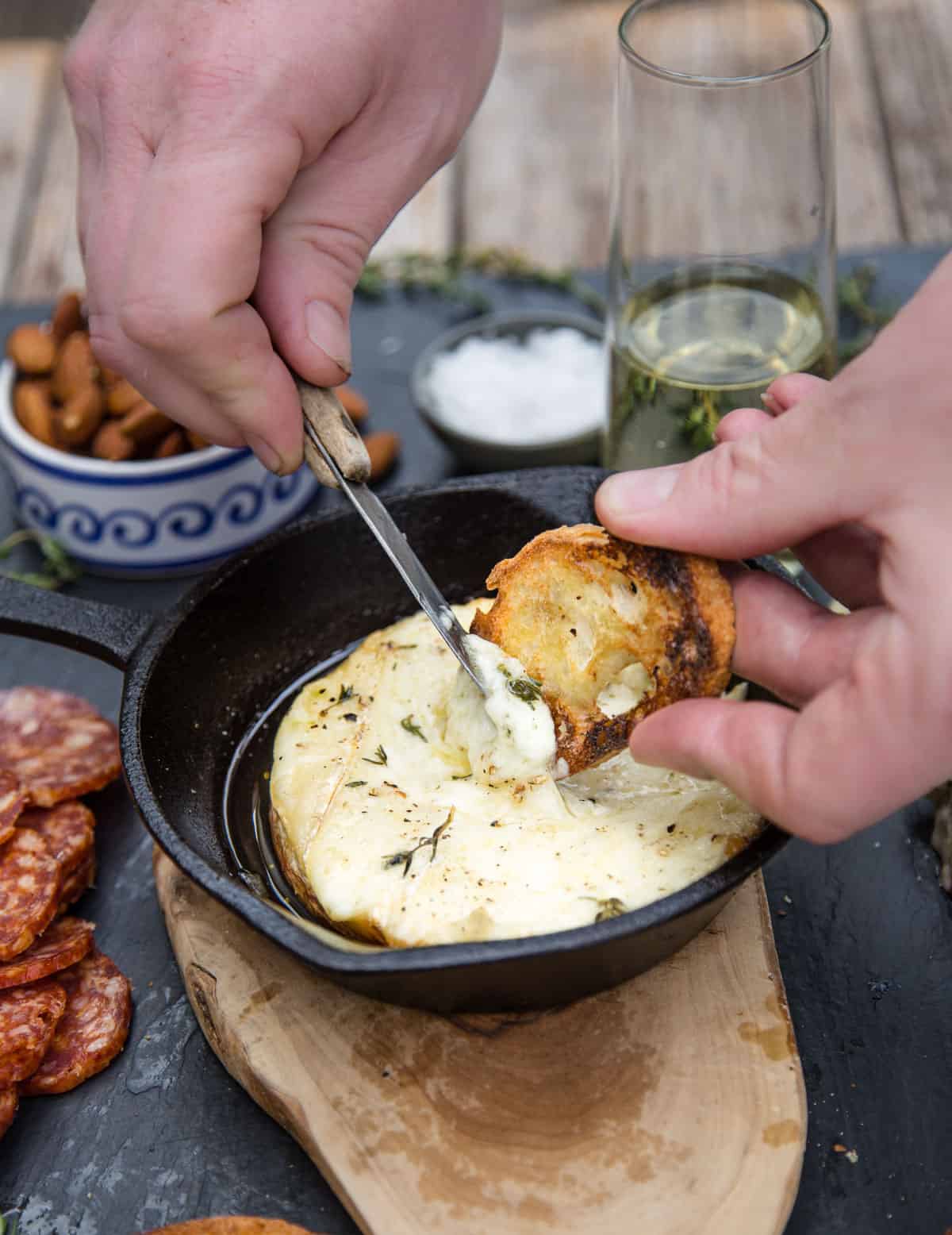 Spreading creamy cheese on a toasted baguette slice