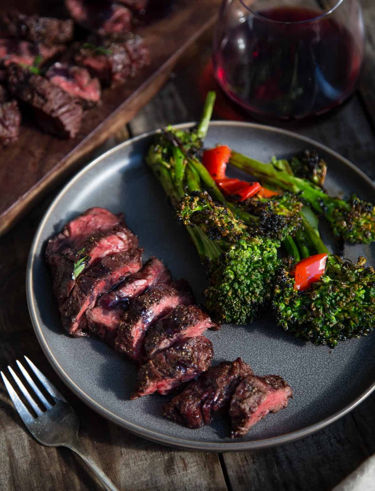 A plate with grilled beef and a side of broccolini