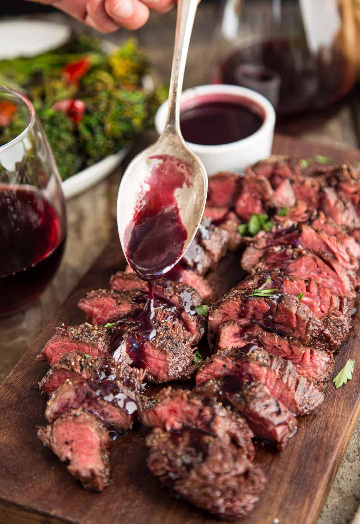 Slices of Grilled Hanger Steak with a wine reduction sauce being poured over the top