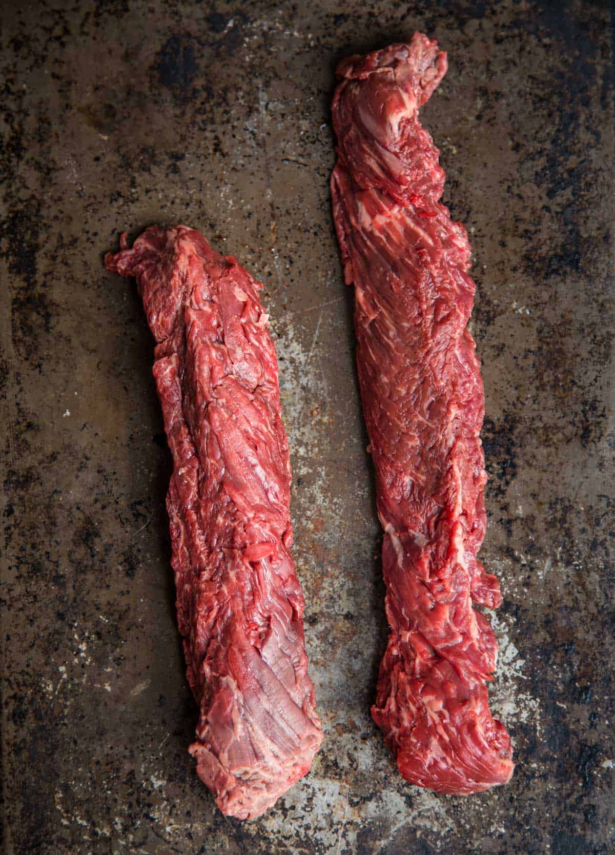 Two raw hanger steaks on a platter