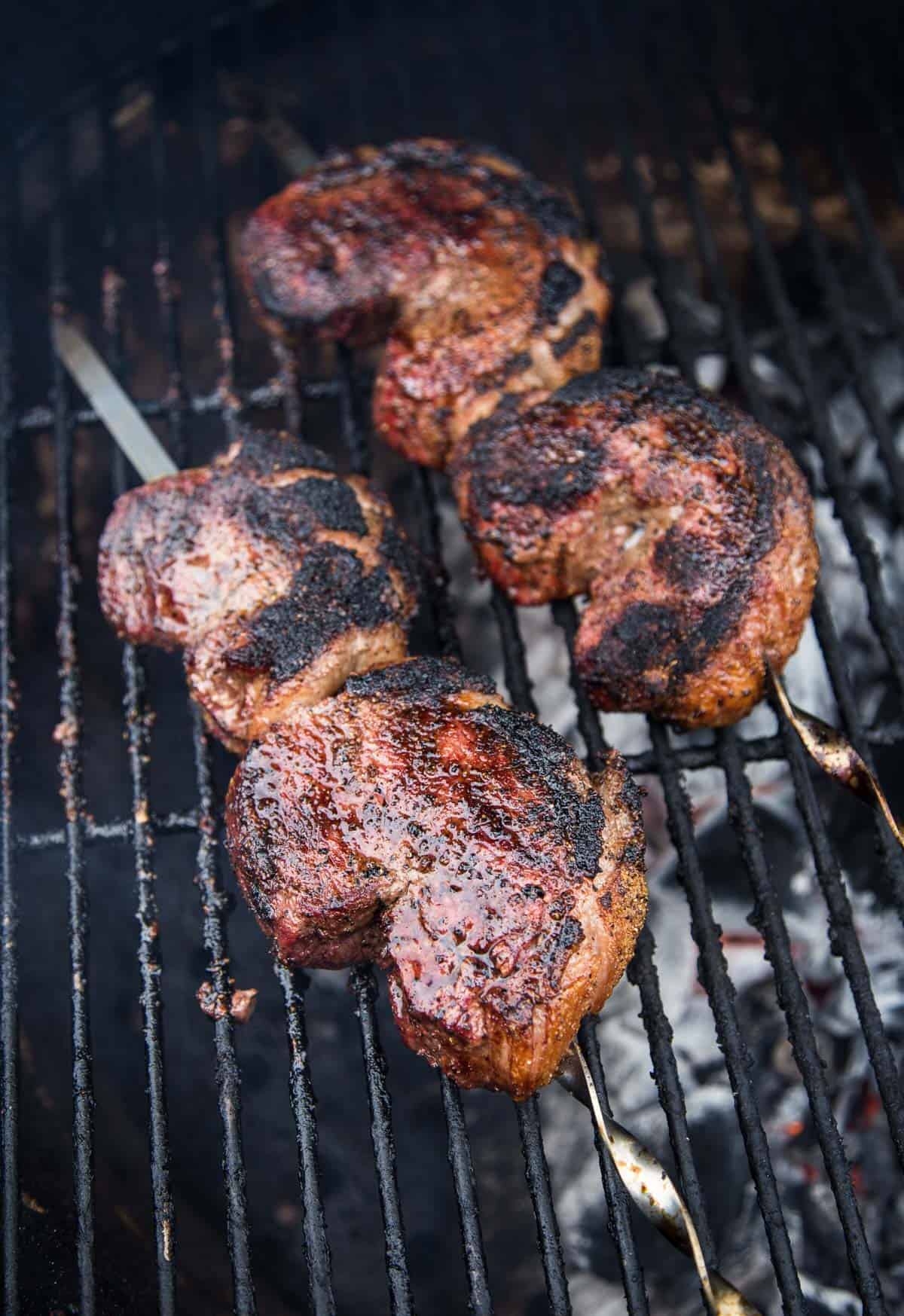 Picanha steaks on a skewer cooking on the grill