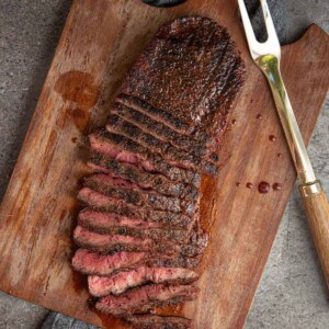 Flat iron steak grilled and sliced on a cutting board.