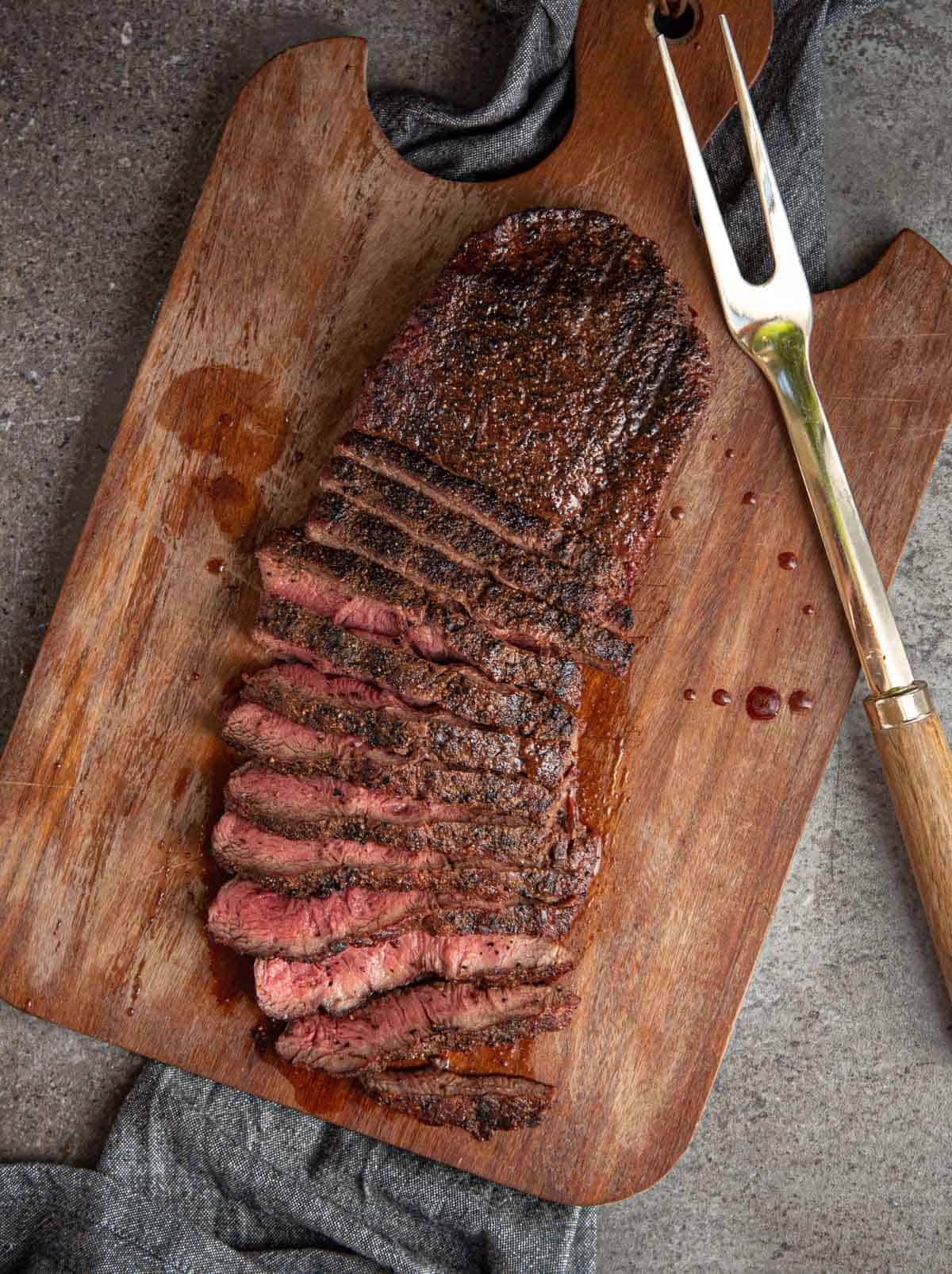 Flat iron steak grilled and sliced on a cutting board.