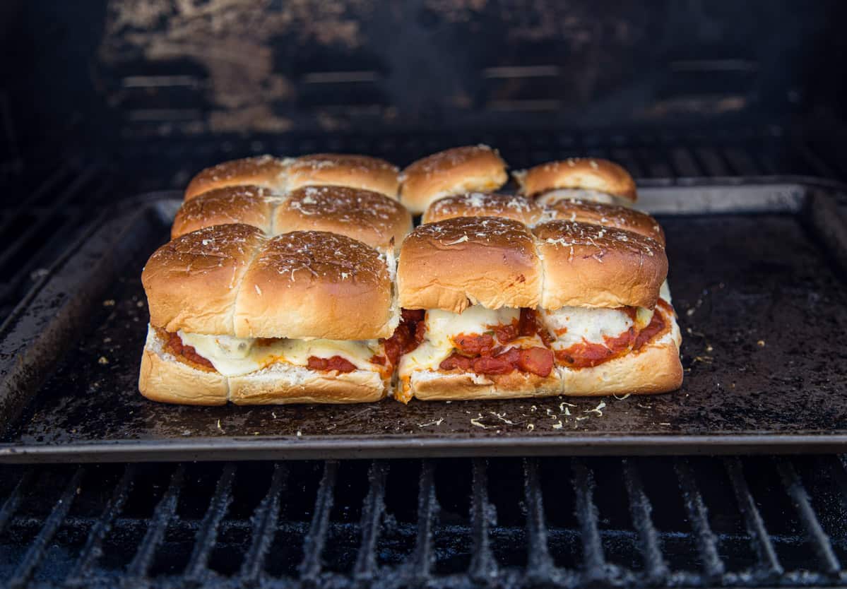 A sheetpan with meatball sliders cooking on the grill