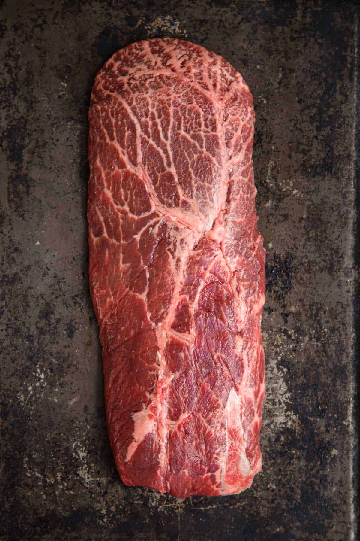 Raw Flat Iron Steak with veins of marbling and pre seasoned.