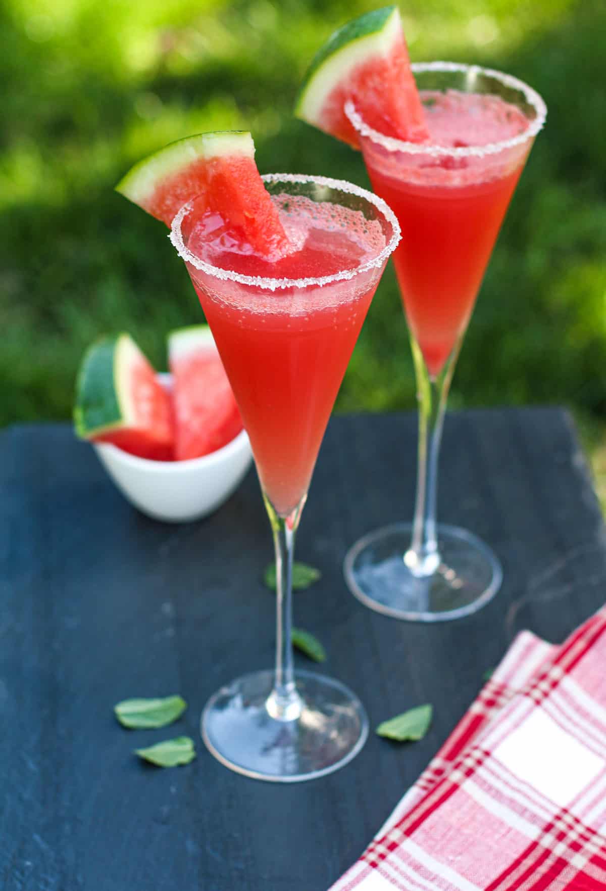 Two watermelon cocktails in wine stems garnished with watermelon wedges