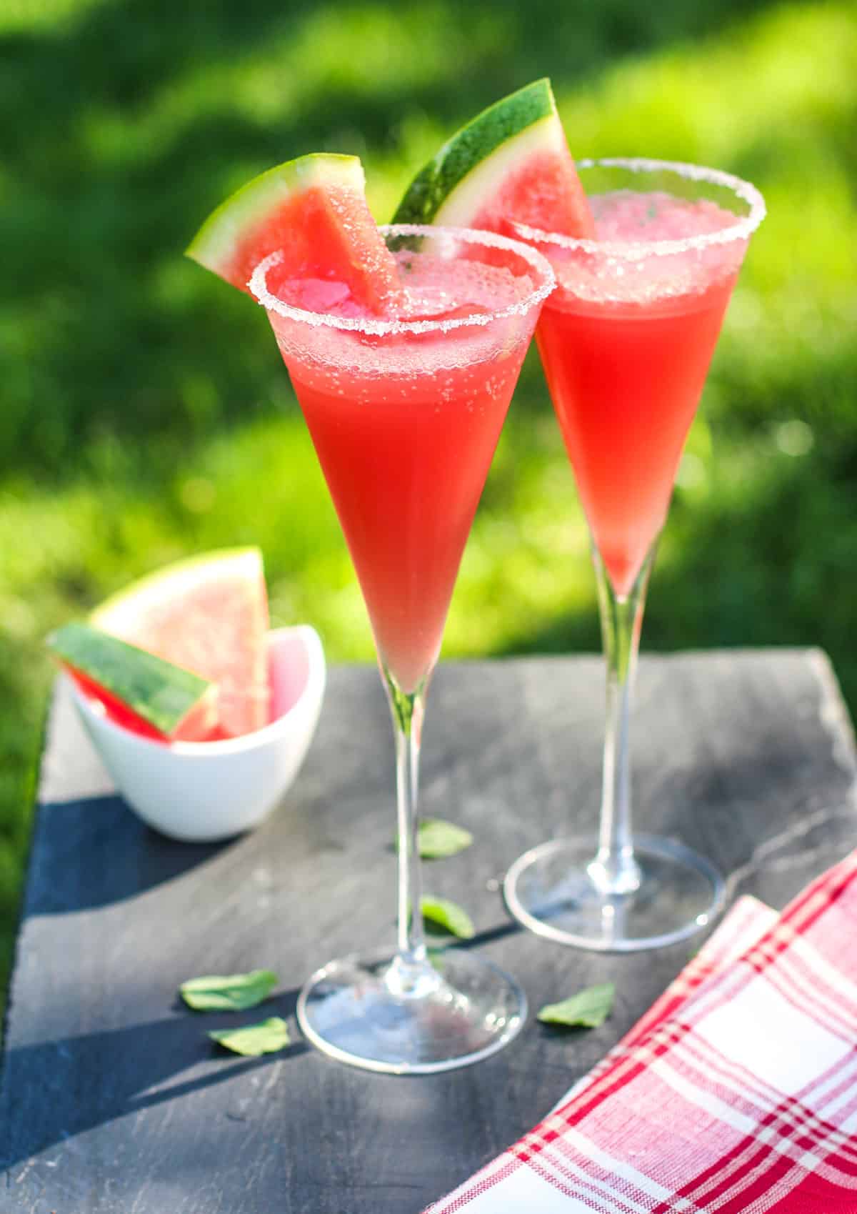 Two Watermelon Cocktails in champagne flutes garnished with watermelon wedges