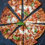 Slices of frozen pizza, cooked, and served on a black slate platter.