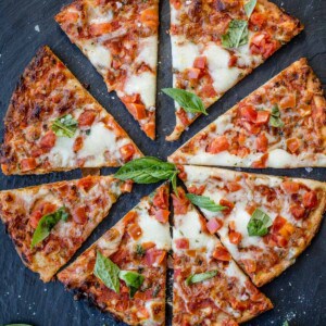 Slices of frozen pizza, cooked, and served on a black slate platter.