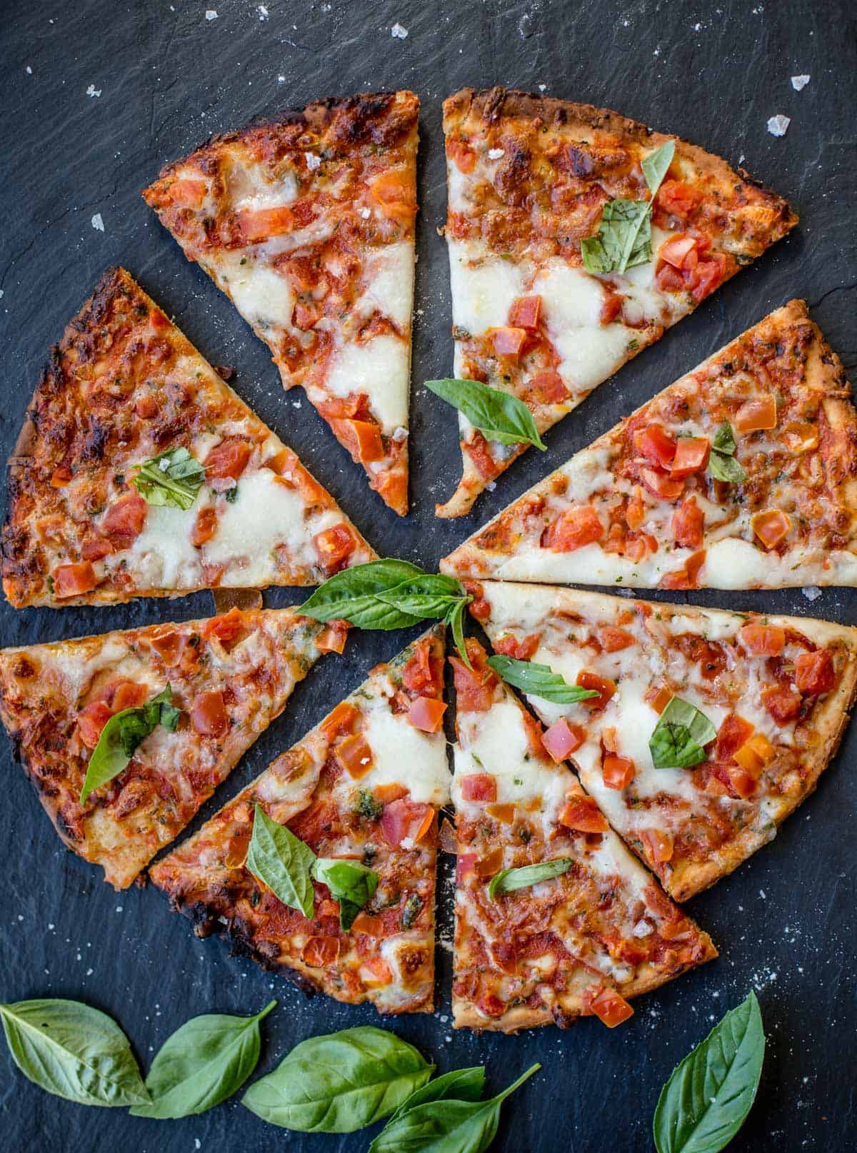 Slices of frozen pizza, cooked, and served on a black slate platter.