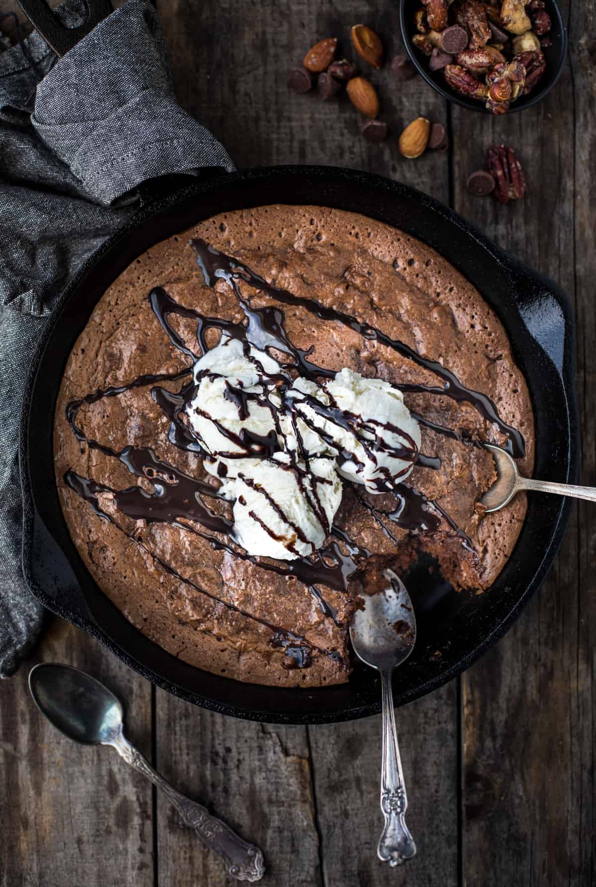 A platter full of Skillet Brownies topped with ice cream and chocolate sauce.
