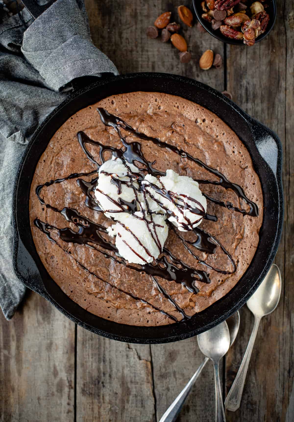 A cast iron pan full of skillet brownies topped with ice cream.