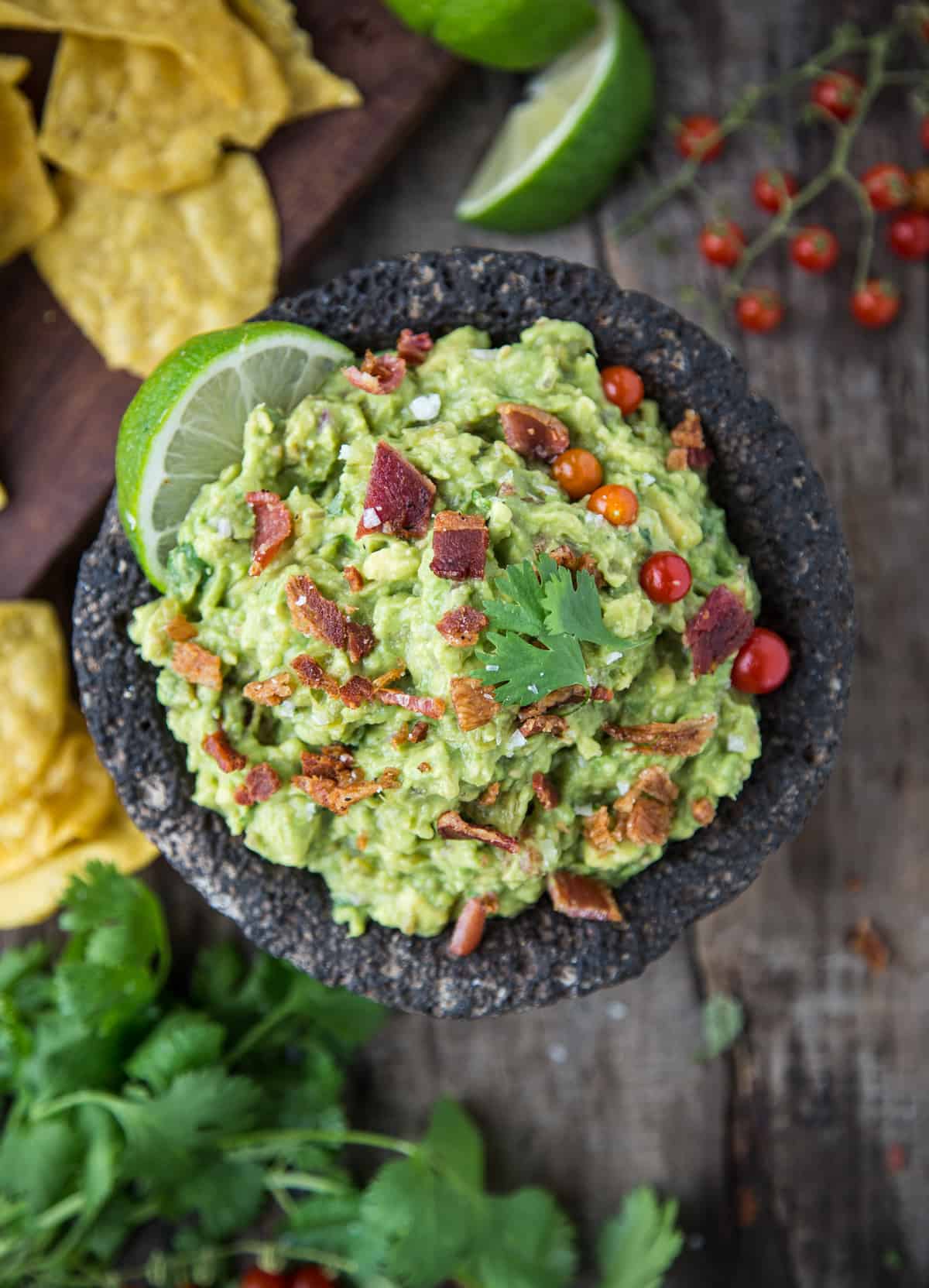 A bowl full of guacamole topped with smoked bacon.