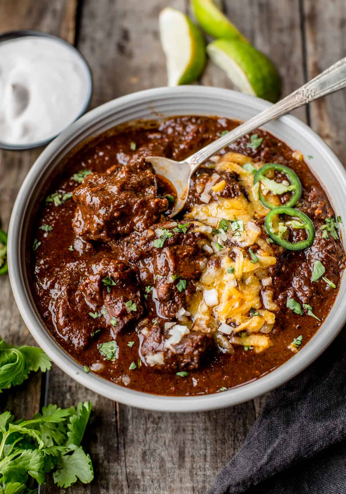 A bowl full of chili topped with cheese and jalapeños 