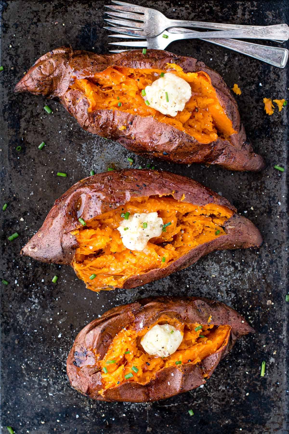 Three Grilled Sweet Potatoes on a sheet pan topped with smoked honey butter