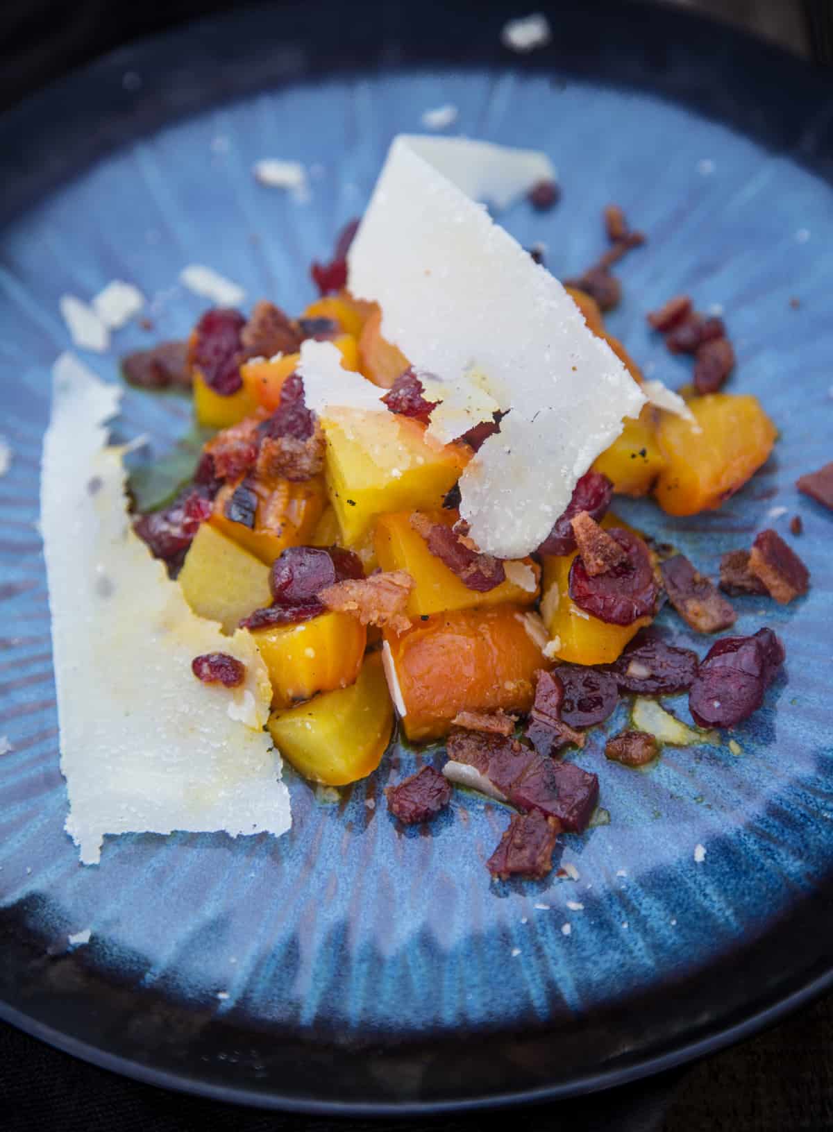 Grilled Beet Salad with cranberries bacon and parmesan cheese on a blue plate