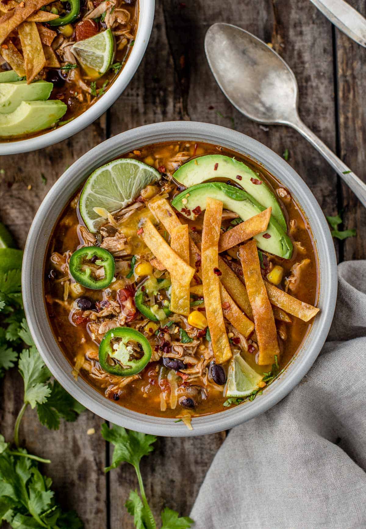 A bowl of Smoked Chicken Tortilla Soup topped with crunchy tortilla strips and avocado