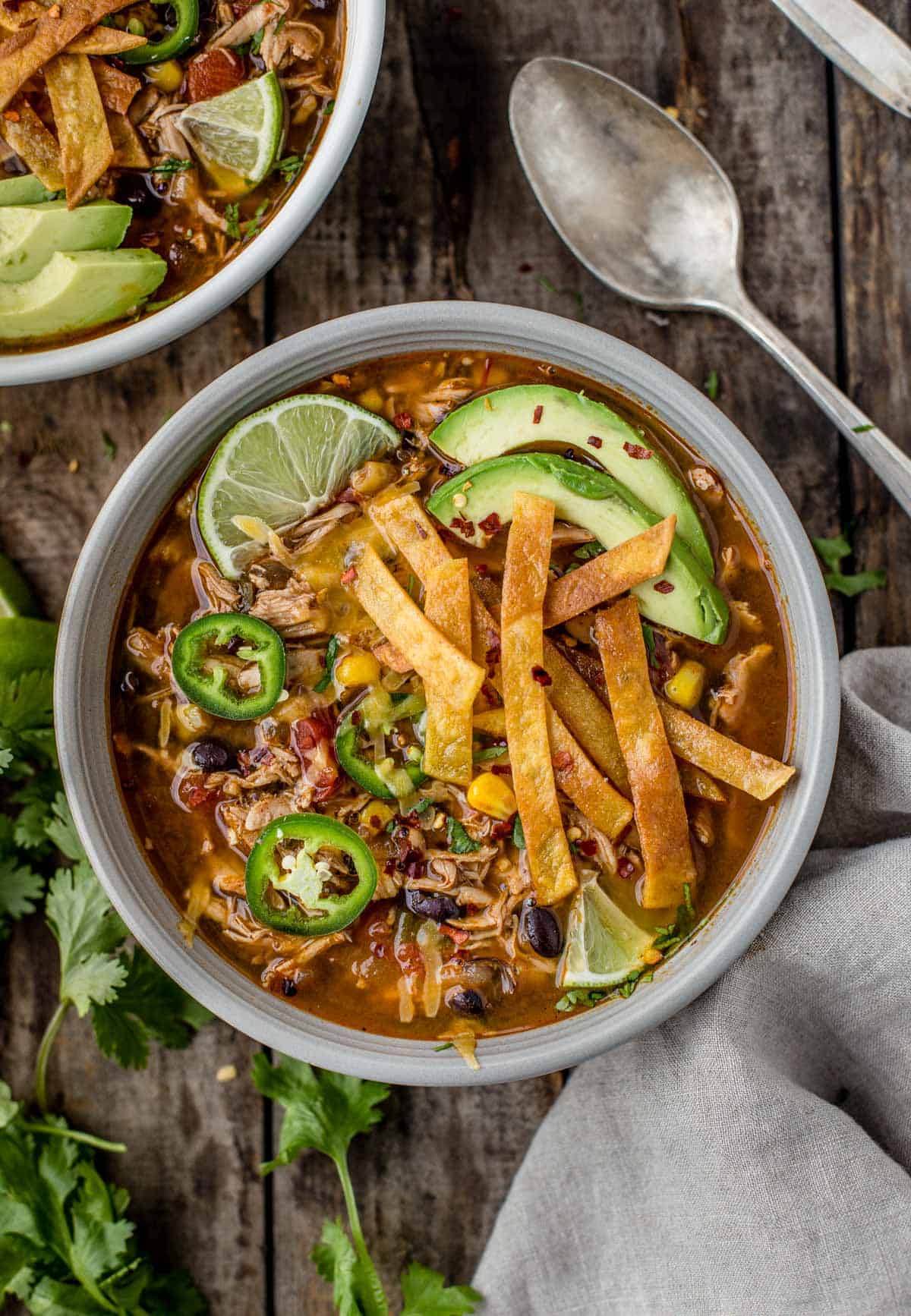 A bowl of Smoked Chicken Tortilla Soup topped with crunchy tortilla strips and avocado 